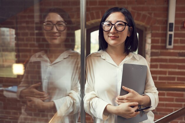 Riuscita donna di affari asiatica che sorride alla macchina fotografica