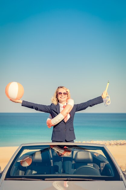 Riuscita giovane imprenditrice sulla spiaggia. Donna in piedi nell'auto classica cabriolet.