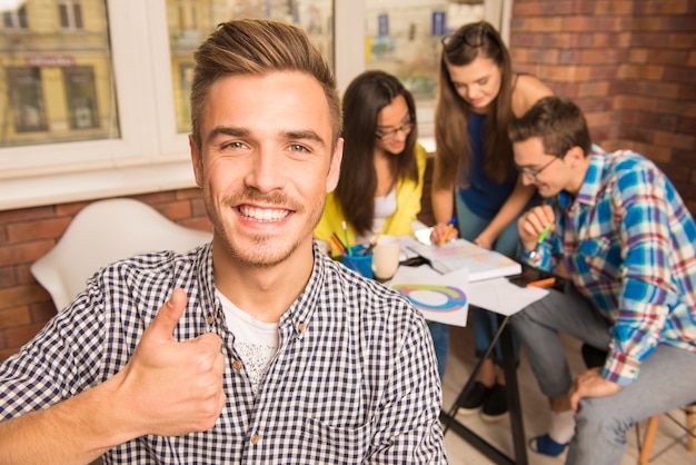 Riuscito giovane gruppo che studia un progetto che gesturing pollice in su