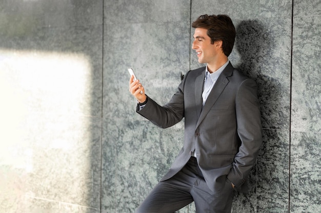 Riuscito giovane uomo d'affari bello usando il telefono all'aperto