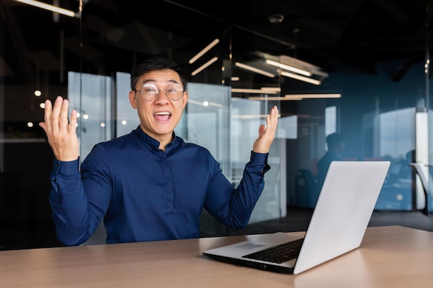 Riuscito uomo d'affari asiatico che celebra la vittoria successo ritratto dell'uomo in ufficio in camicia casual