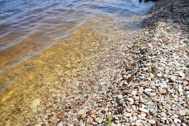 riva del fiume con acqua e ciottoli, primo piano