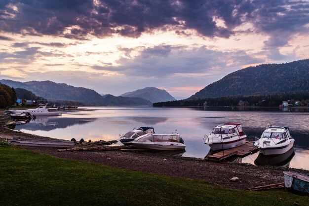 Riva del lago con barche a motore ormeggiate all'alba Lago Teletskoye Artybash Village Altai Russia