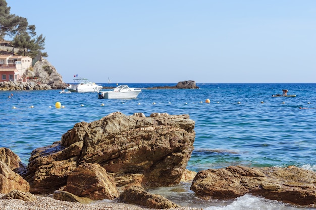 Riva del mare roccioso con Pebble Beach, onde, cielo blu