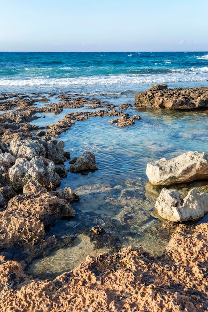 Riva rocciosa del mare turchese sullo sfondo di un cielo azzurro e limpido Bei paesaggi e relax Verticale