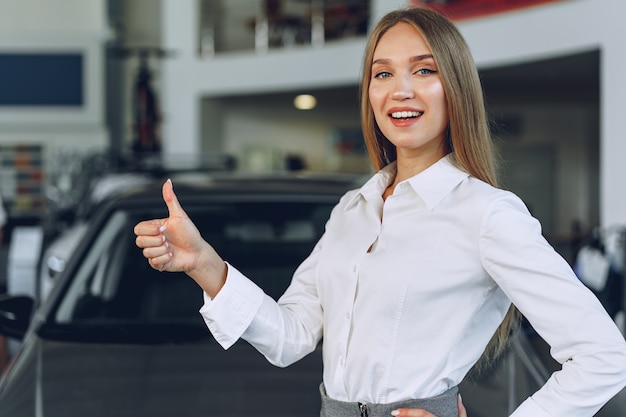 Rivenditore di auto felice bella giovane donna in showroom