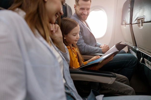 Rivista di lettura della bambina con i genitori in aereo