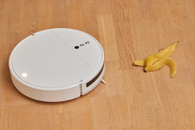 Robot aspirapolvere su pavimento in legno laminato tecnologia di pulizia intelligente banana