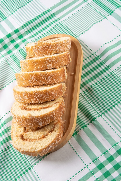 Rocambole, affettato â€‹â€‹rocambole farcito con dulce de leche su un vassoio di legno su un tavolo con tovaglia a scacchi. sfondo scuro, messa a fuoco selettiva.