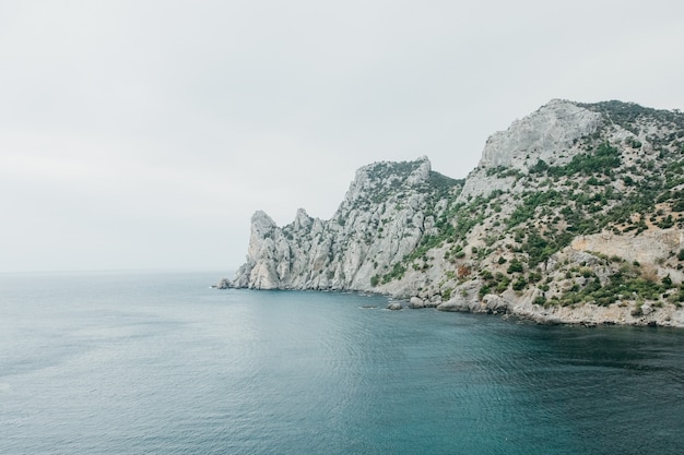 Rocce e un mare nebbioso di acqua blu