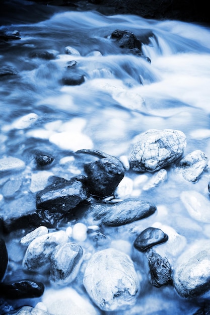 Rocce in un fiume con acqua che scorre lungo il lato