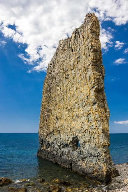 Roccia di forma insolita sulla cornice verticale delle pietre della riva del mare