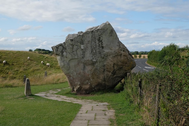 Roccia quadrata gigante in un prato con pecore in Inghilterra