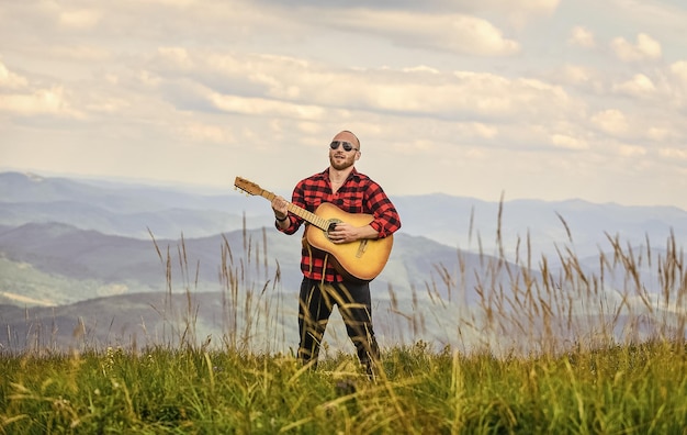 Rock con te uomo sexy con chitarra in camicia a scacchi hipster moda western campeggio ed escursionismo uomo cowboy felice e libero con suonatore di chitarra acustica canzone di musica country