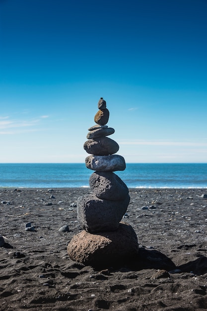 Rock of fortune. Un mucchio di pietre sulla spiaggia di sabbia nera in Vik, Islanda.