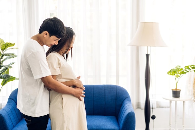 Romantica coppia asiatica dolce marito che abbraccia e sorride bellezza asiatica incinta wifeMan che si aspetta con la gravidanza della donna tenere il bambino nella pancia a casa