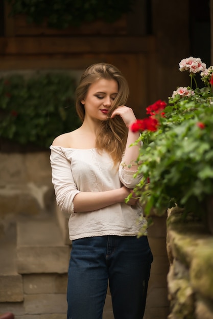 Romantica modella bionda che indossa abiti alla moda, posa per strada con fiori a Lvov