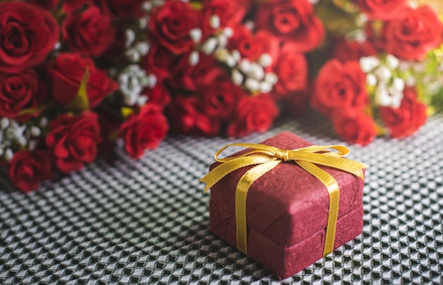 Romantica natura morta piccola confezione regalo e rose rosse su sfondo di seta per il giorno di compleanno di San Valentino