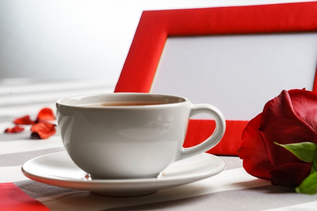 Romantico still life con una tazza di tè e attributi di vacanza rosso brillante.