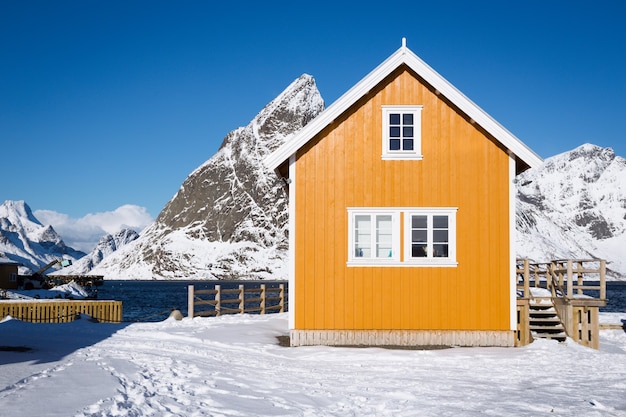 Rorbu tradizionale norvegese in legno per stare sulla riva del fiordo e delle montagne in lontananza. Isole Lofoten. Norvegia.