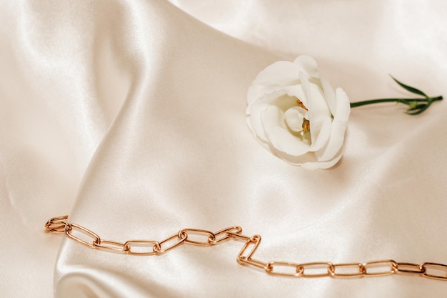 Rosa bianca su fondo beige seta con decorazioni dorate spazio per testo
