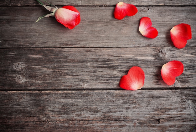 Rosa e petalo nel cuore della forma su fondo di legno