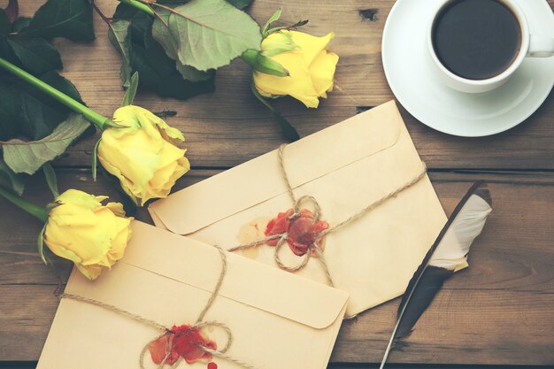 Rosa gialla con lettere e caffè sul tavolo