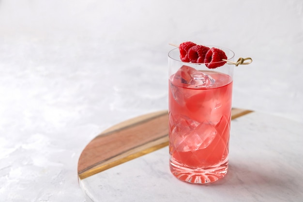 Rosa rosa cocktail ghiacciato con lampone in cristallo sul tavolo