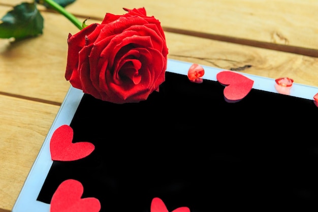 Rosa rossa e cuori decorativi sulla tavoletta modello Valentine's Day Wedding o Mother's Day biglietto di auguri Copia spazio per il testo