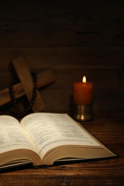 Rosario di croce della Bibbia e candela della chiesa su un tavolo di legno
