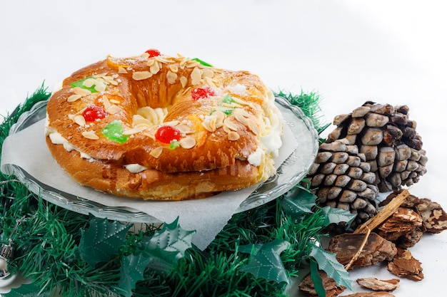 Roscon de Reyes ripieno di crema su sfondo bianco e tre bambole re