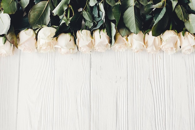 Rose bianche su sfondo di legno piatto disteso con spazio per il testo Mockup di biglietto di auguri floreale Invito a nozze o concetto di felice festa della mamma Elegante bouquet di fiori bianchi