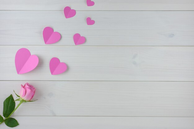 Rose e cuori rosa su una tavola di legno bianca, fondo di giorno di S. Valentino, vista superiore.