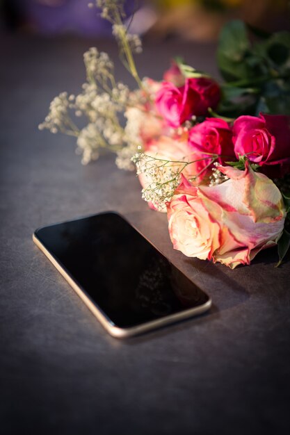 Rose e smartphone rosa sul tavolo