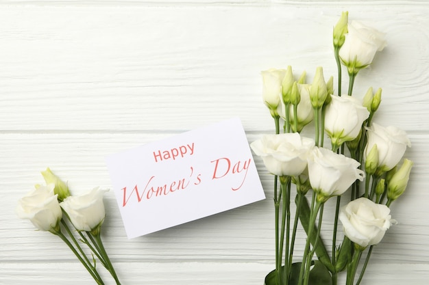 Rose e testo Happy Women's Day su fondo di legno bianco