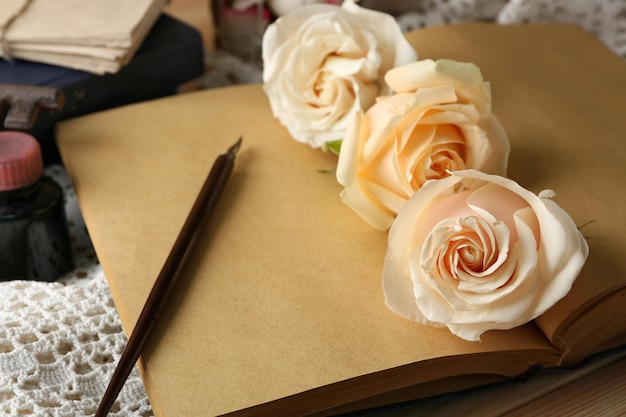 Rose fresche con il vecchio libro, la chiave e le lettere sul fondo della tavola di legno. Concetto d'epoca