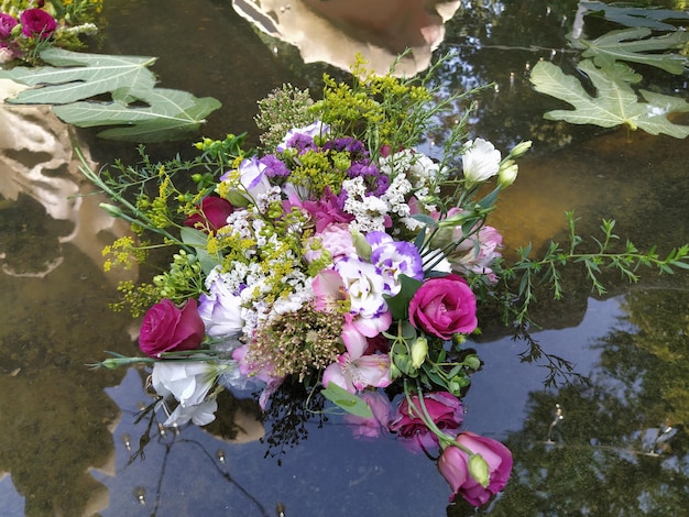 Rose rosa e rosse in un bouquet che galleggia nell'acqua di uno stagno Germogli colti come decorazione per una vacanza estiva Ivan Kupala solstizio d'estate Festa del raccolto