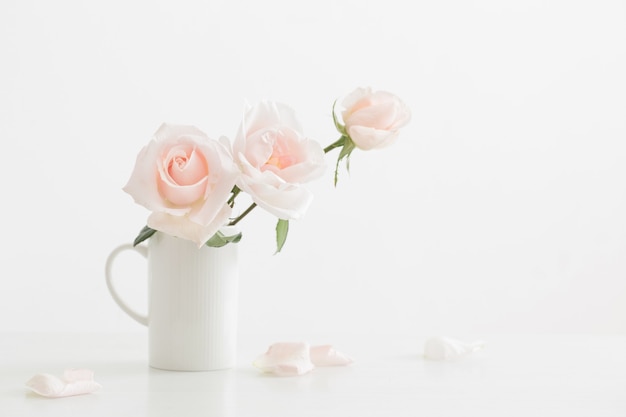 Rose rosa in tazza bianca sulla tavola di legno bianca