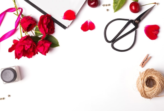 Rose rosse, ciliegie e forbici isolato primo piano