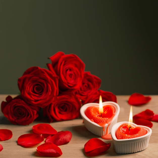 Rose rosse con candele accese su sfondo scuro