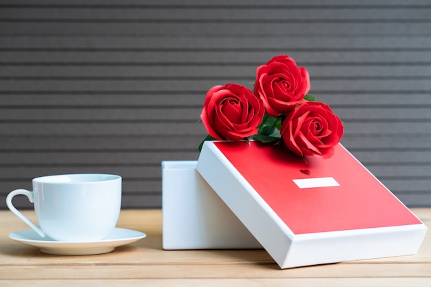 Rose rosse e confezione regalo su legno