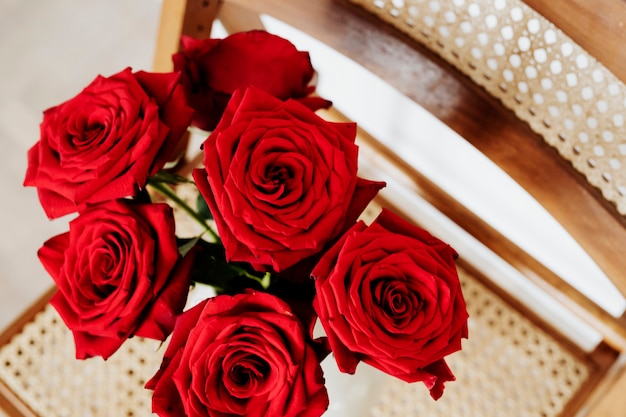 Rose rosse in un vaso bianco su una sedia di legno