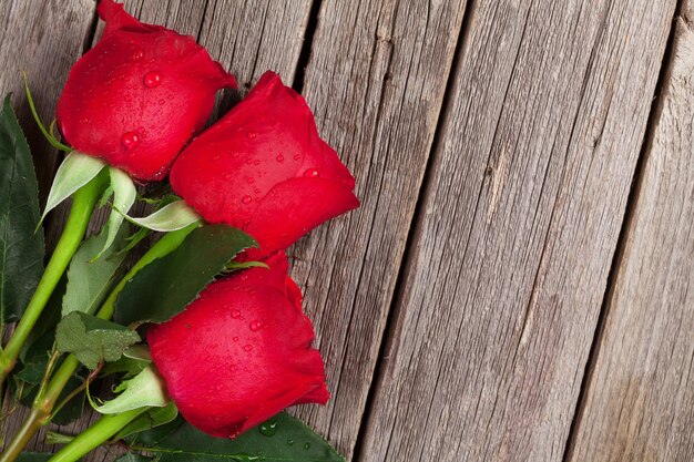 Rose rosse su tavola di legno