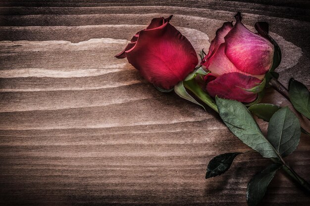 Rose rosse sul concetto di vacanze di tavola di legno