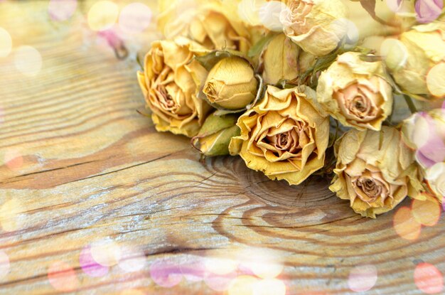 Rose secche su fondo di legno vecchio Concetto di fiori morti Transizione della giovinezza e della bellezza