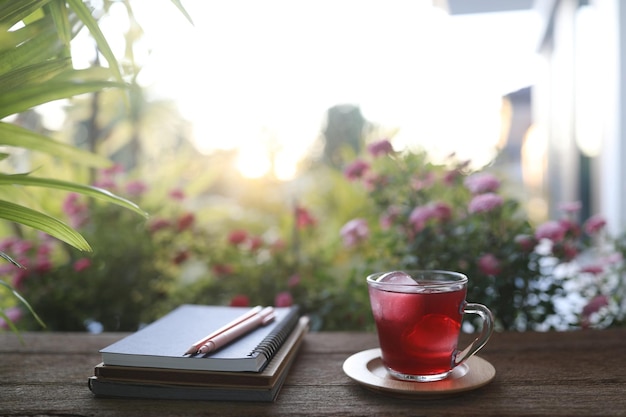 Roselle bevanda a base di erbe e taccuino e fiori a margherita sulla tavola di legno all'aperto