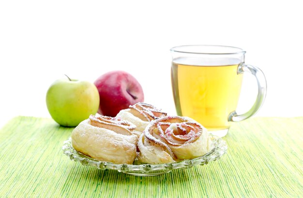 Rosette di mele nel tè di pasta sfoglia e due mele su un primo piano del tavolo