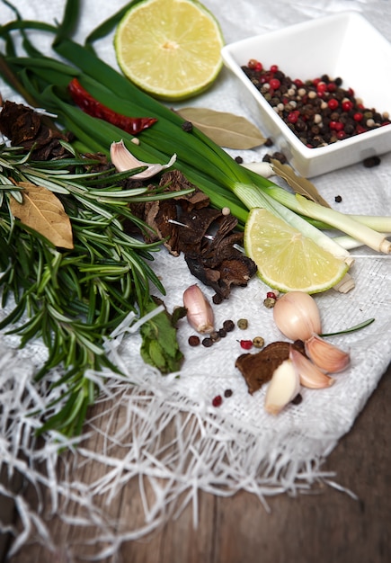 Rosmarino, lime, peperoncino, aglio, funghi secchi sul tavolo di legno.