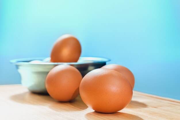 Rosolare le uova di gallina in una ciotola d'argento su tavola di legno