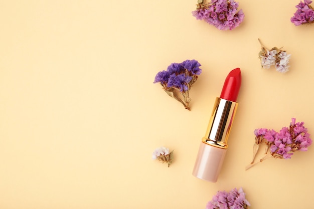 Rossetto con bellissimi fiori sul tavolo beige con copia spazio